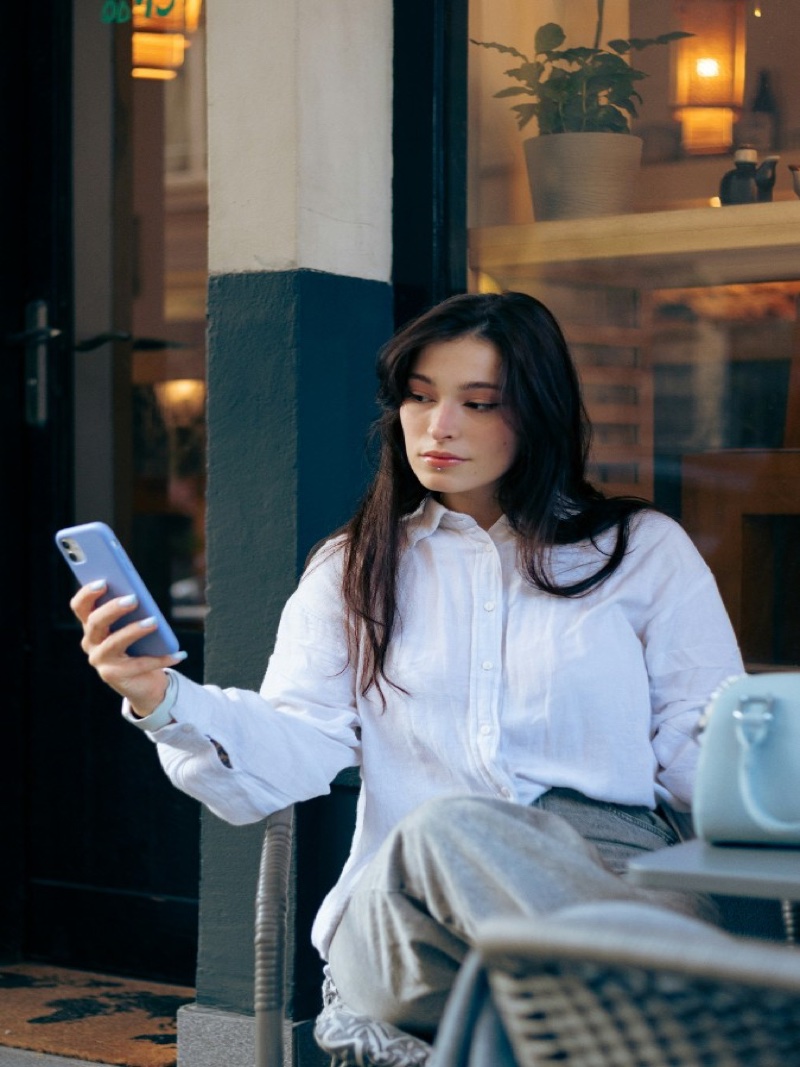 Young woman smiling while using her smartphone at an outdoor café