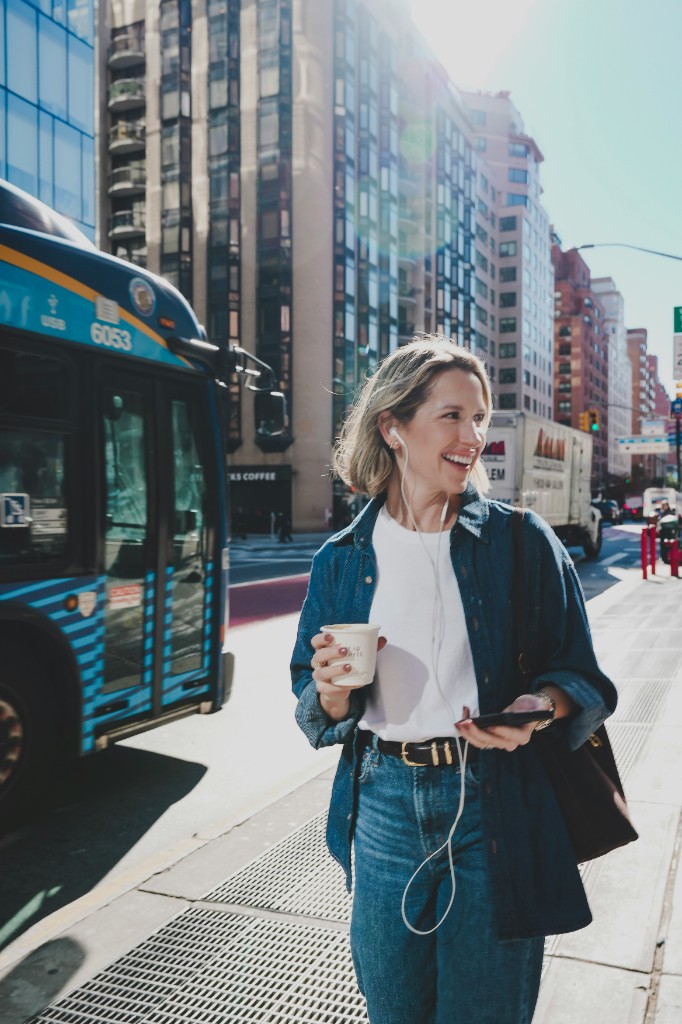 Young professional walking in the city while using her smartphone