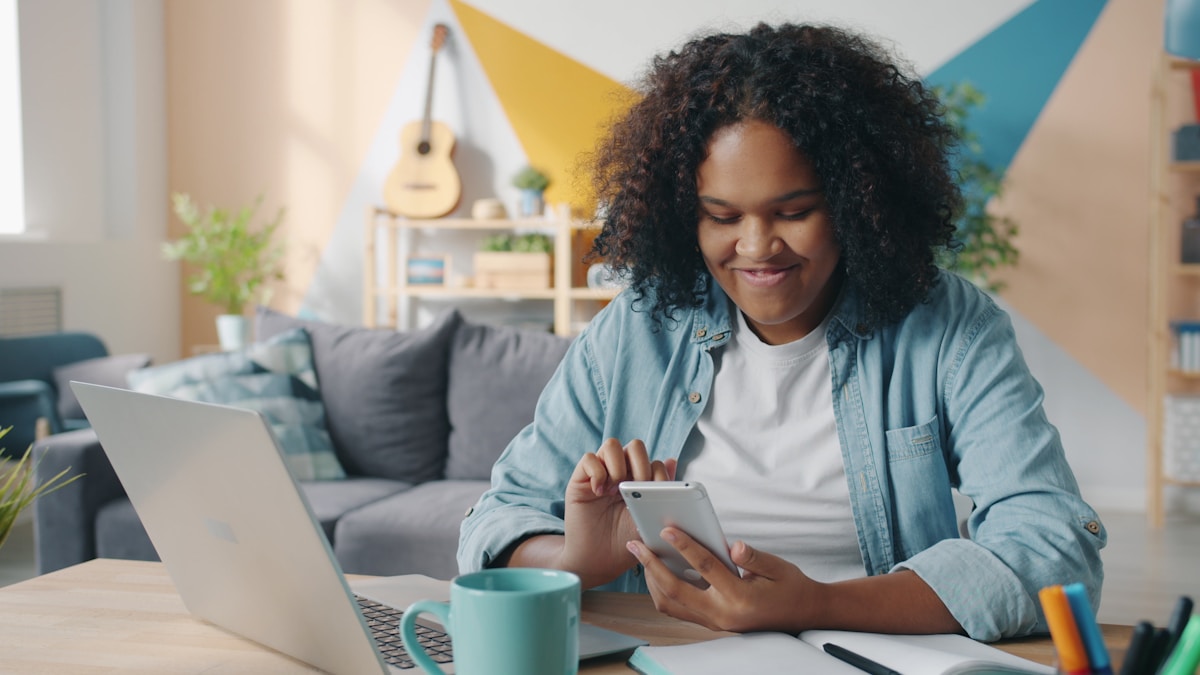 Woman smiling while using her smartphone at a desk